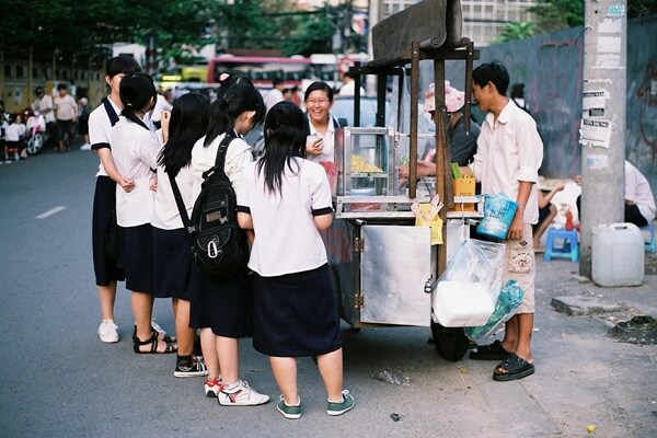 Bán đồ ăn vặt trước cổng trường thu hút nhiều bạn học sinh đến ăn